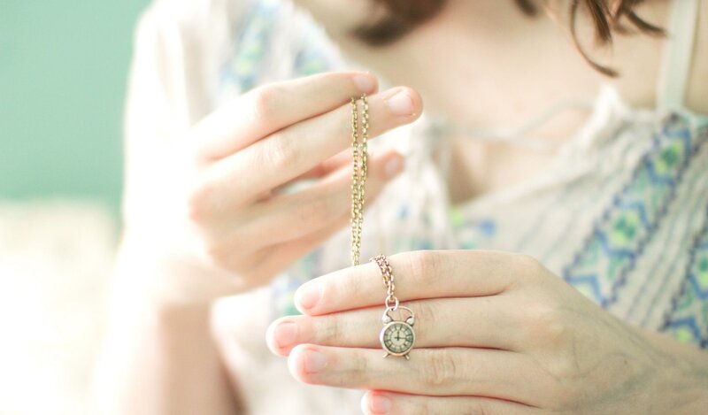woman holding a clock necklace