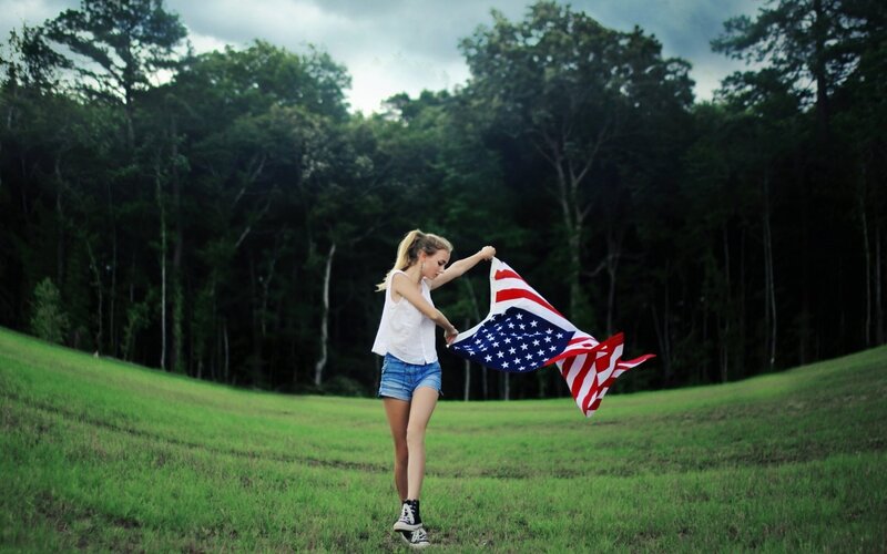 Woman holding American flag in field