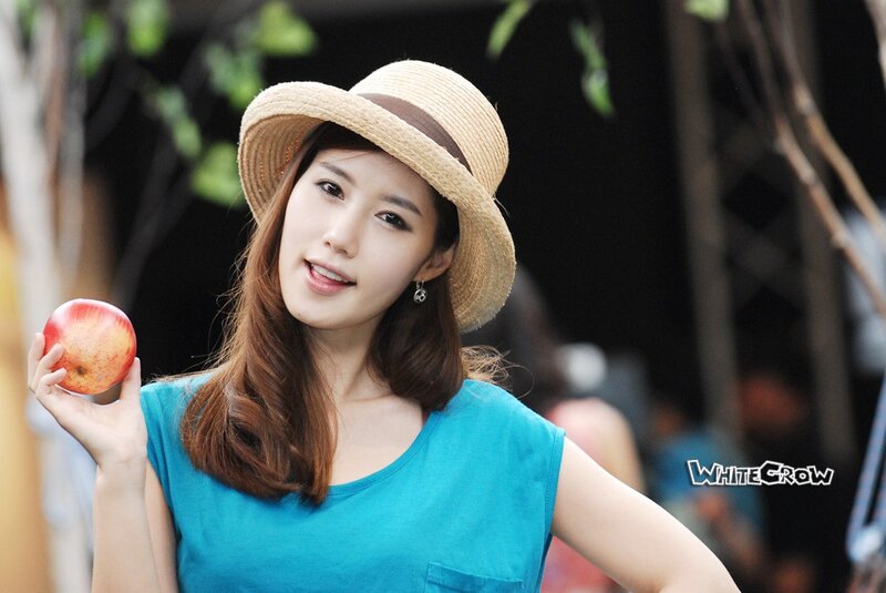 woman holding apple in hat