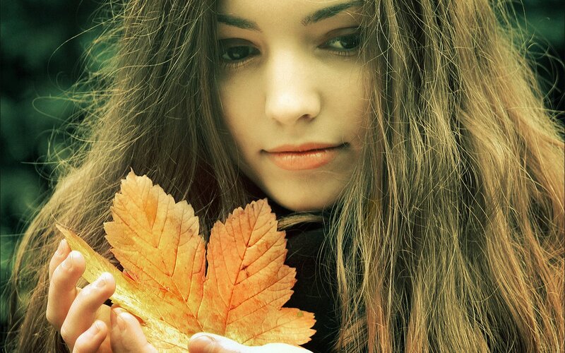 woman holding autumn leaf