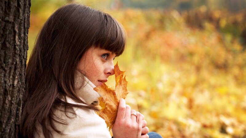 woman holding autumn leaf