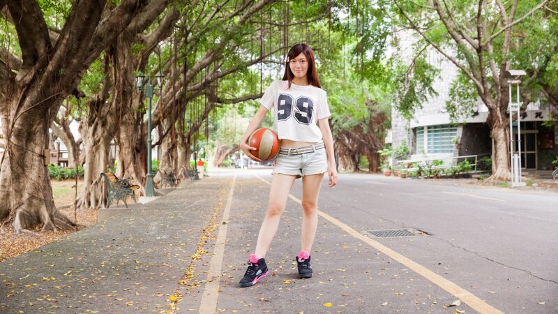 woman holding basketball on tree-lined path