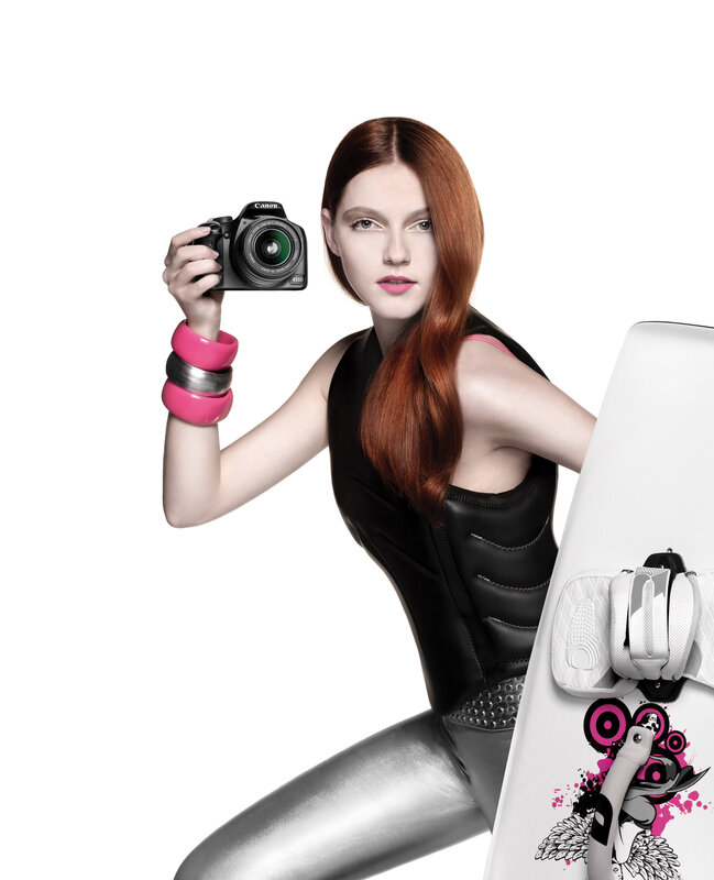 Woman holding camera and surfboard