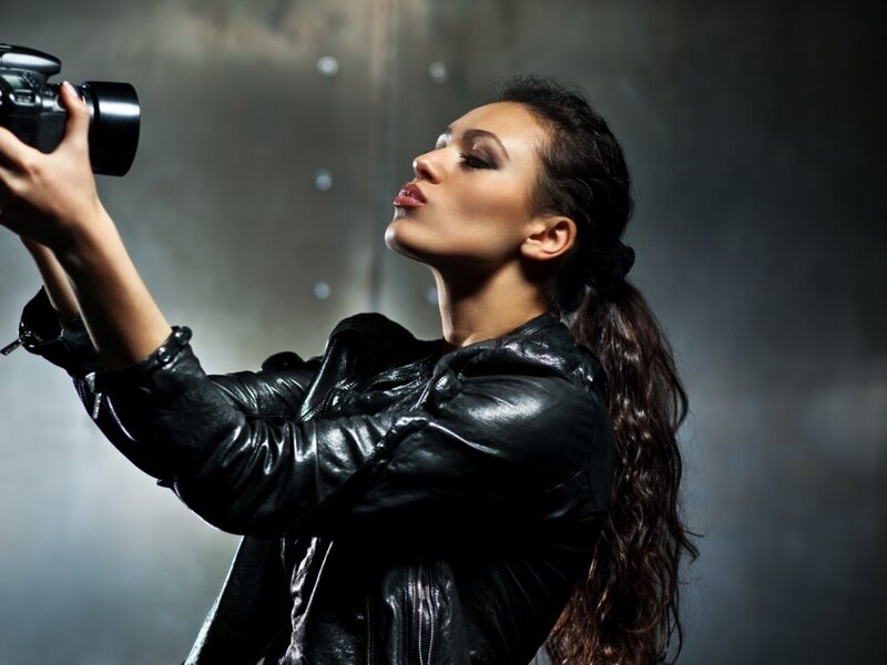 Woman Holding Camera — Black, Dramatic, Photograph, Leather Jacket