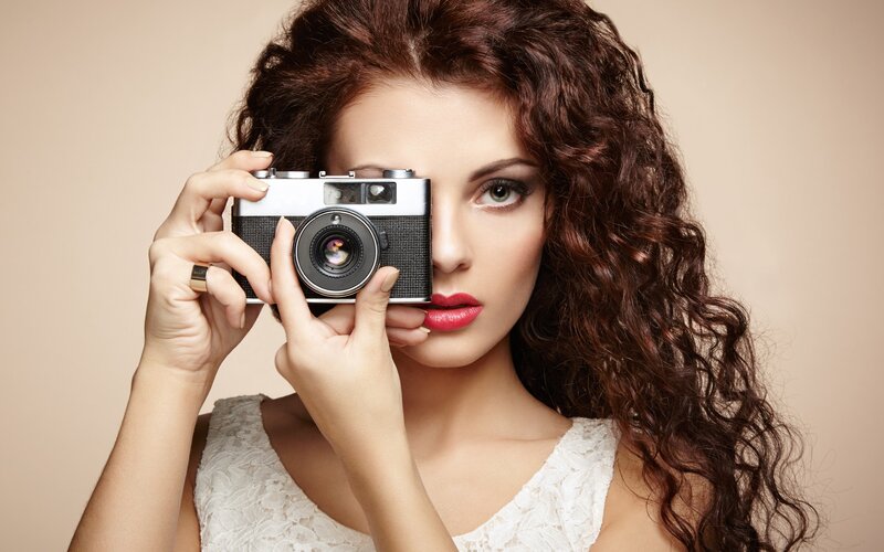 Woman Holding Camera — Brown, Confident