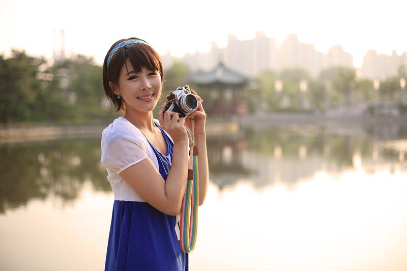 Woman holding camera by lake