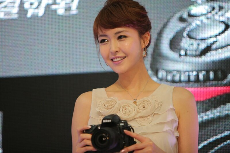 Woman Holding Camera — White, Smiling