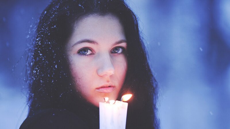 woman holding candle in snow