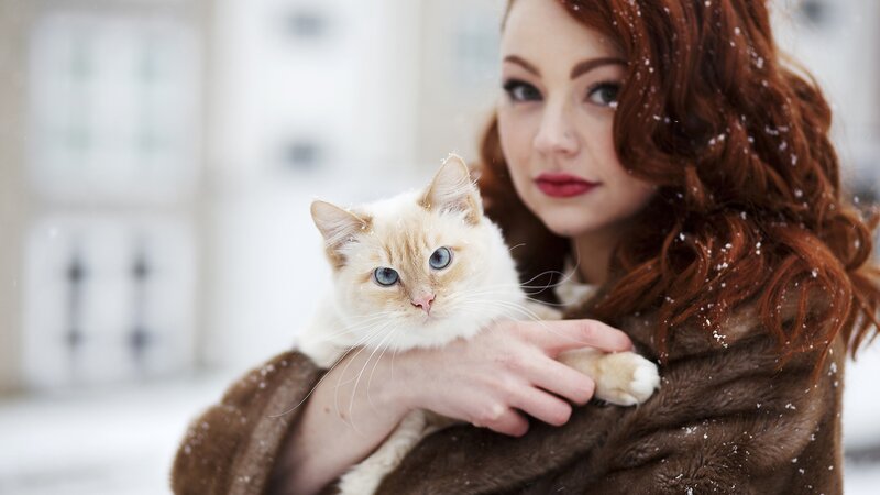 Woman holding cat in snow
