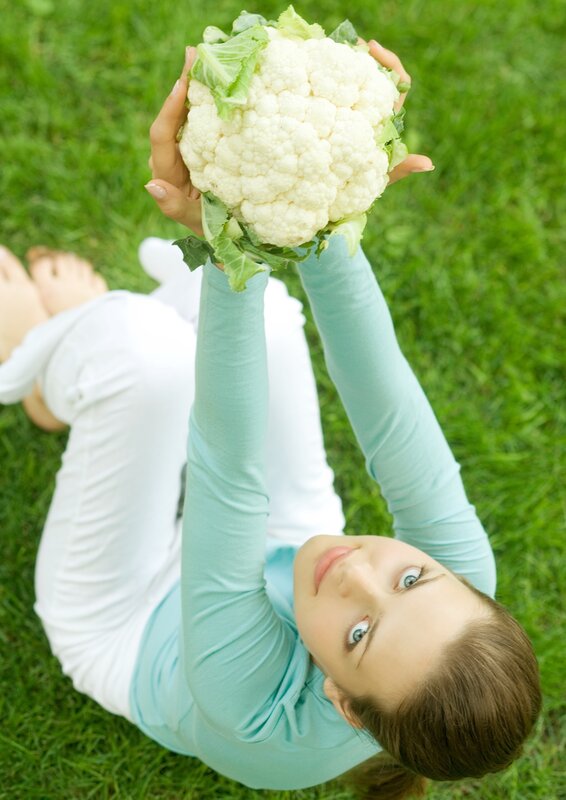 woman holding cauliflower on grass