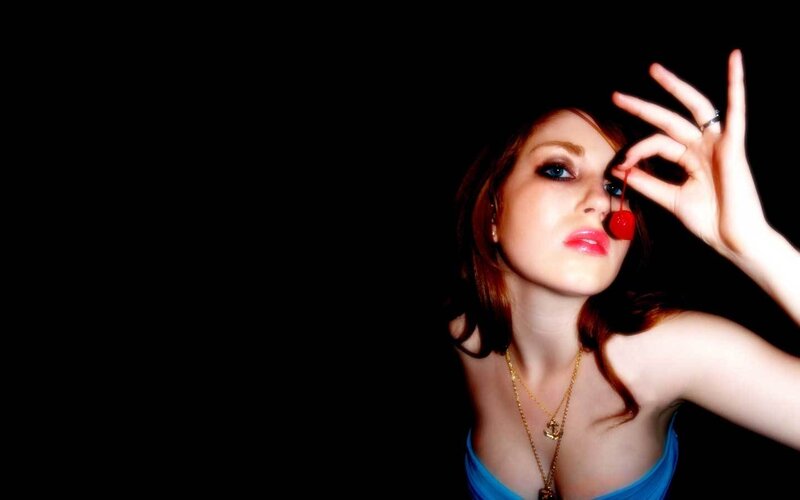 woman holding cherry near eye