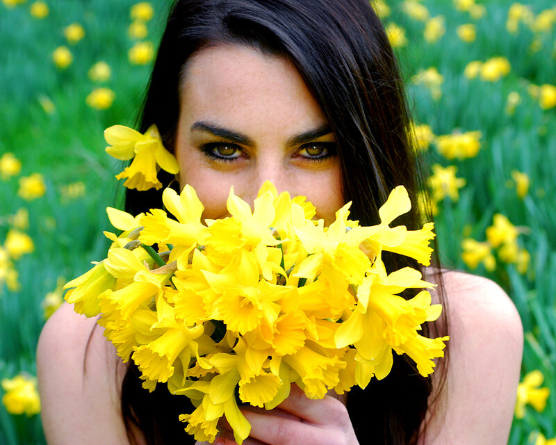 woman holding daffodils in field