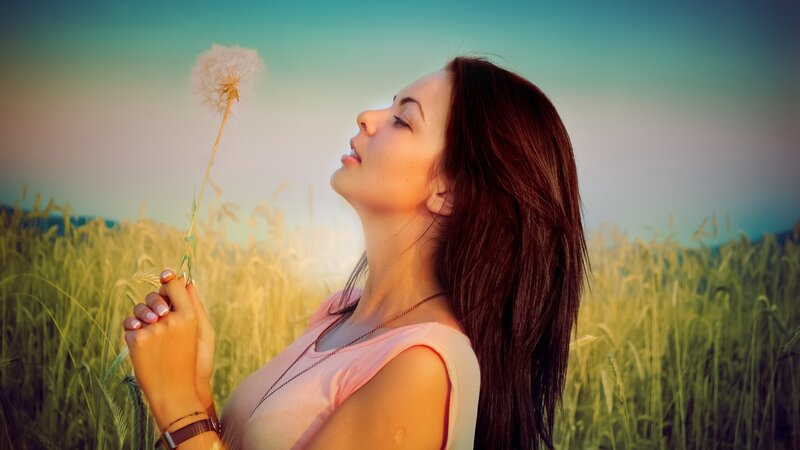 woman holding dandelion in field