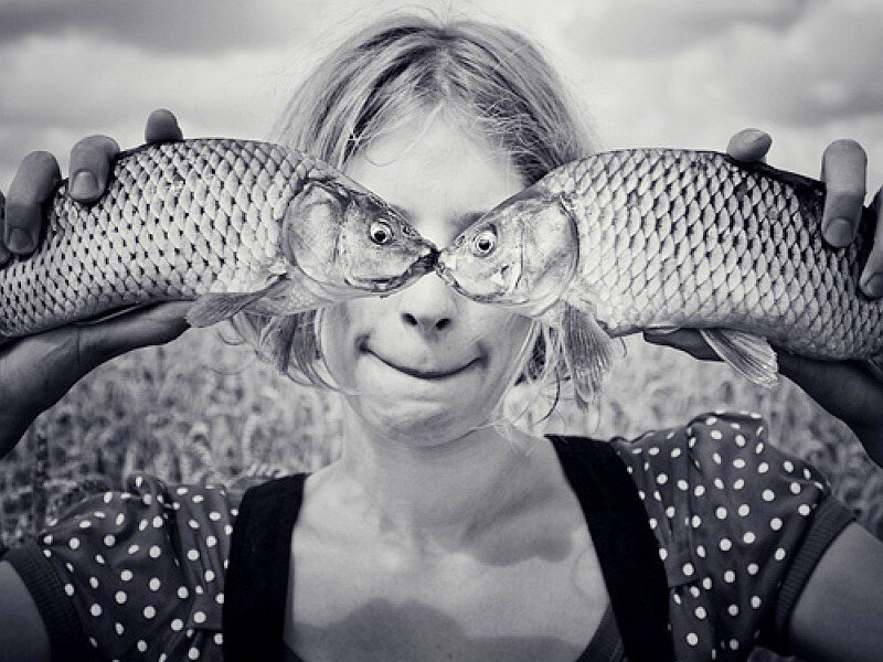 woman holding fish over eyes