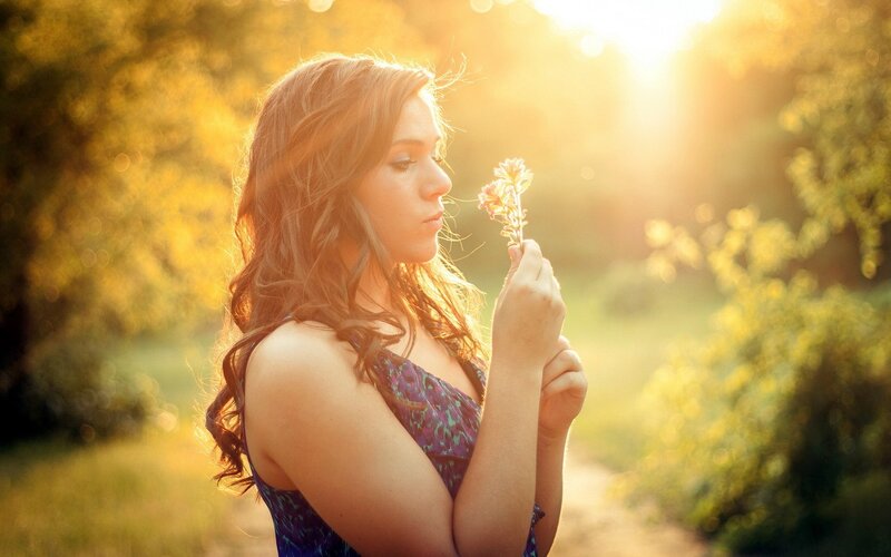 woman holding flower in sunlight