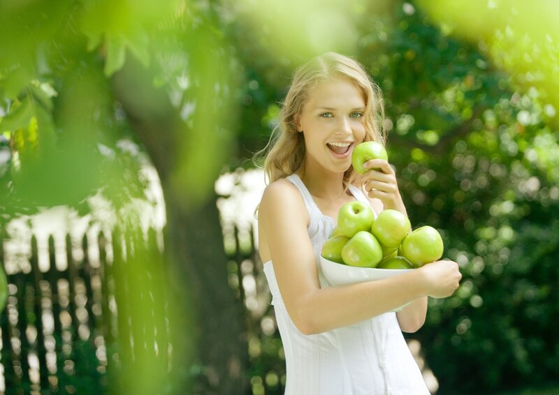 woman holding green apples