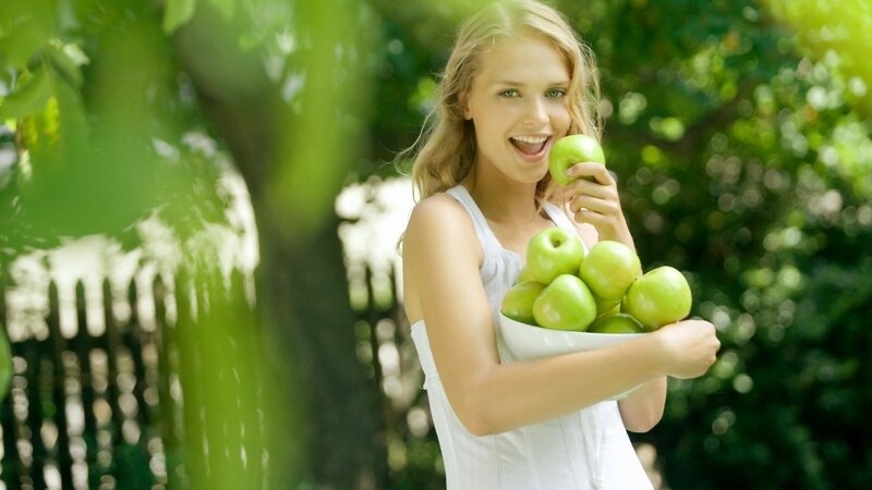 woman holding green apples