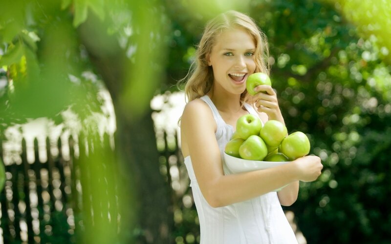 woman holding green apples