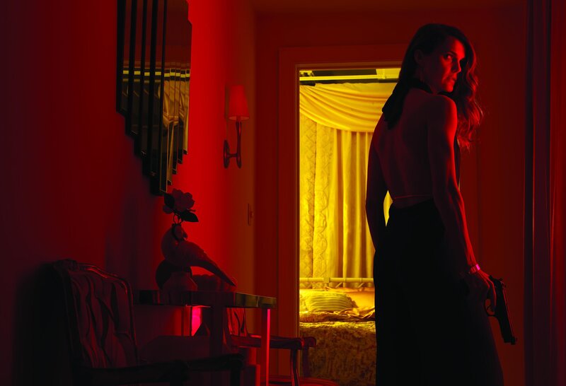 Woman holding gun in red room