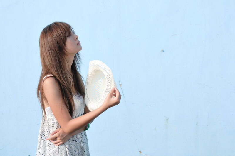 woman holding hat against blue wall