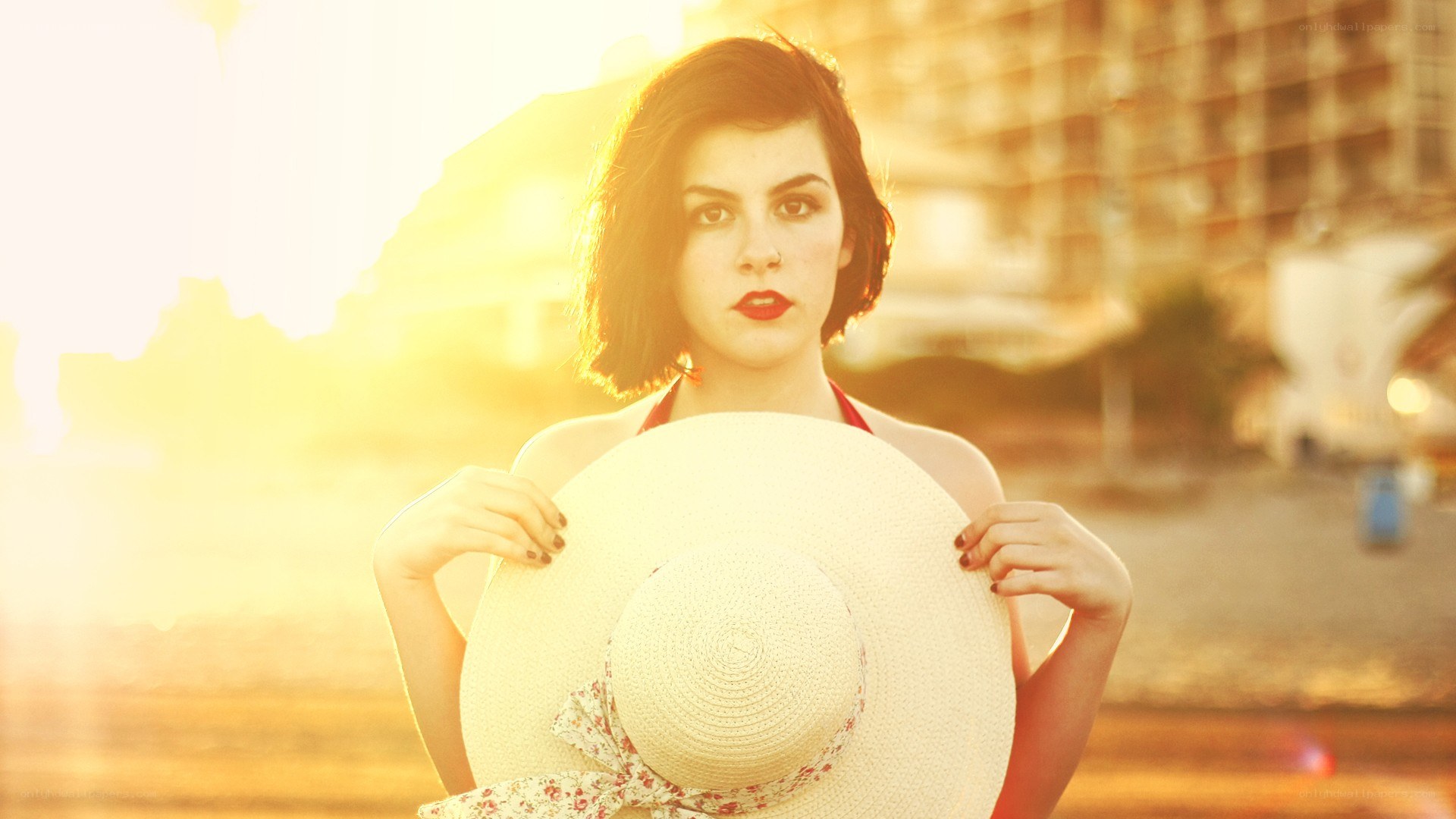 woman holding hat at sunset