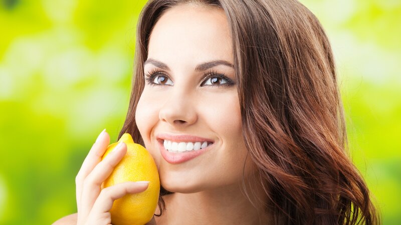 woman holding lemon outdoors