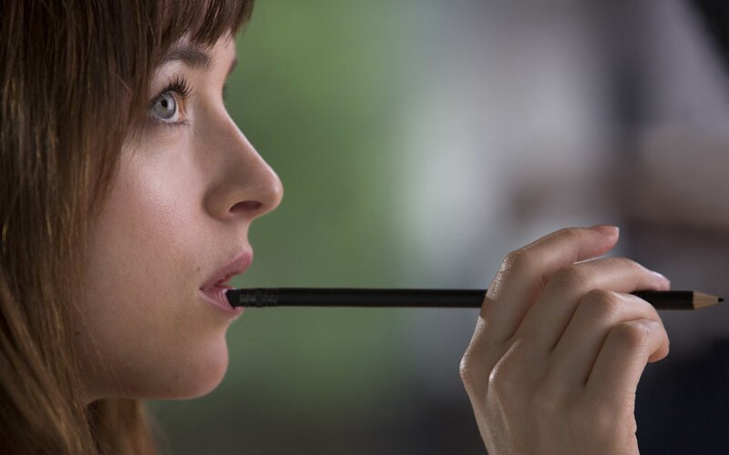 woman holding pencil to mouth