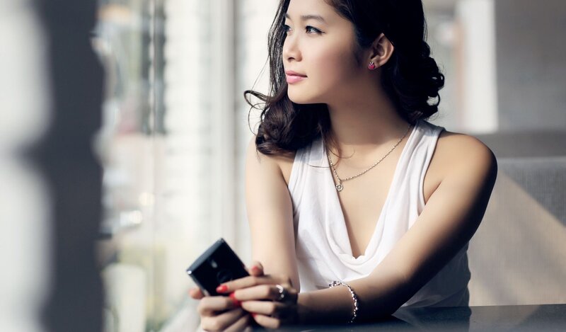 woman holding phone by window