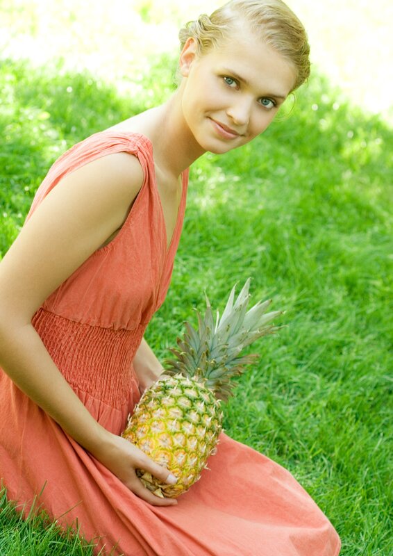 woman holding pineapple in grass