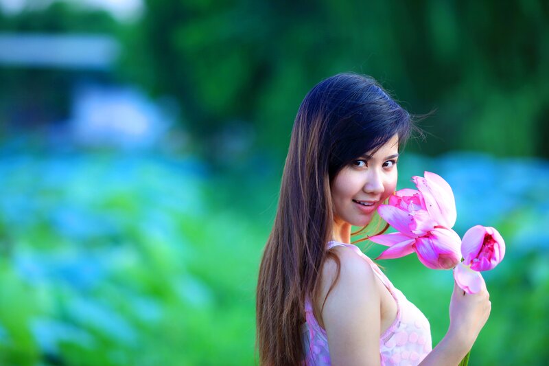 woman holding pink lotus flower