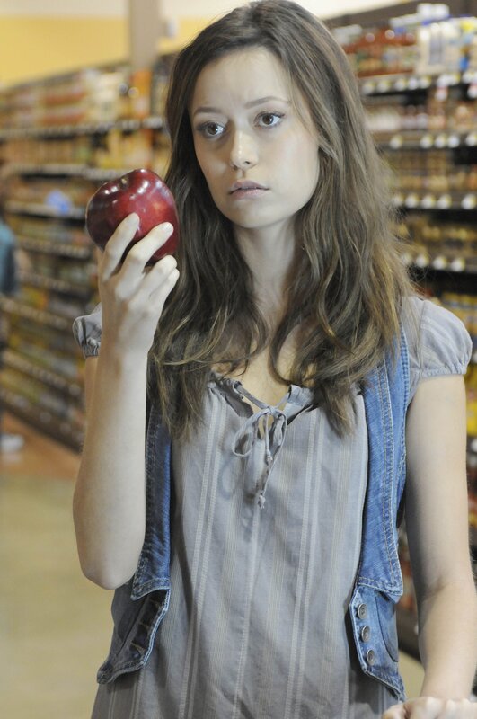 woman holding red apple in store