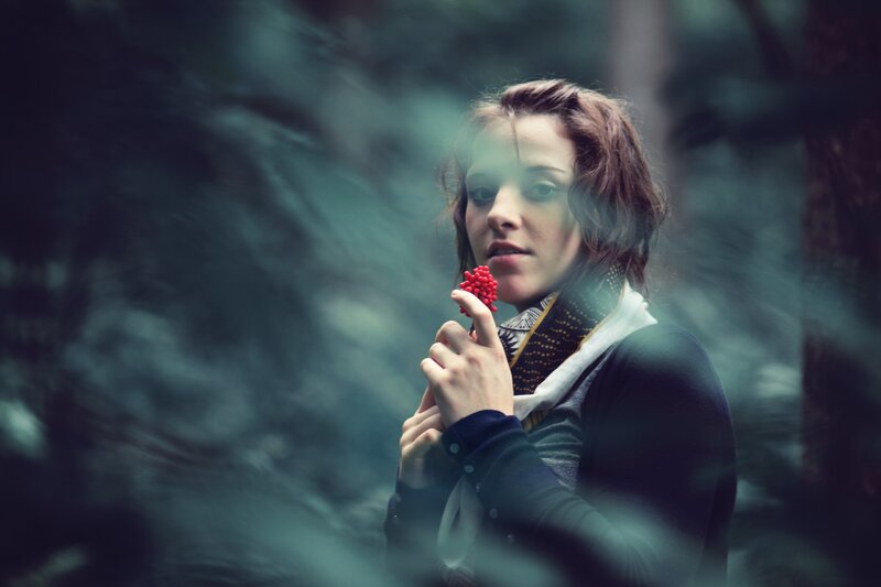woman holding red berry in forest