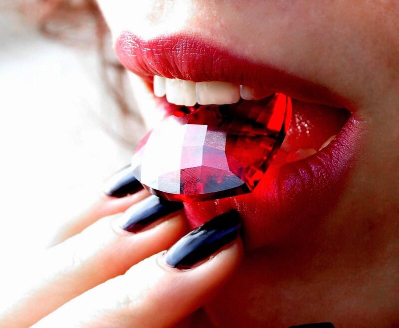 woman holding red gemstone
