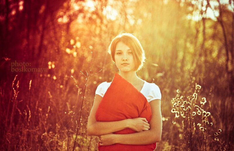 woman holding red pillow in field