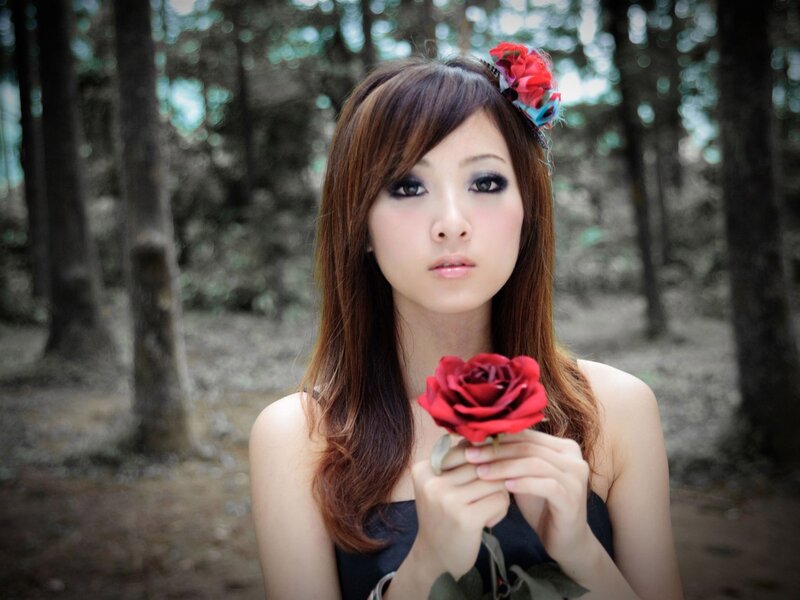 woman holding red rose in forest
