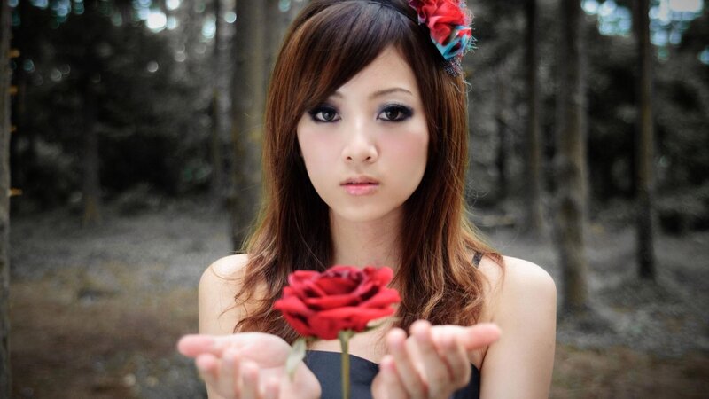 woman holding red rose in forest