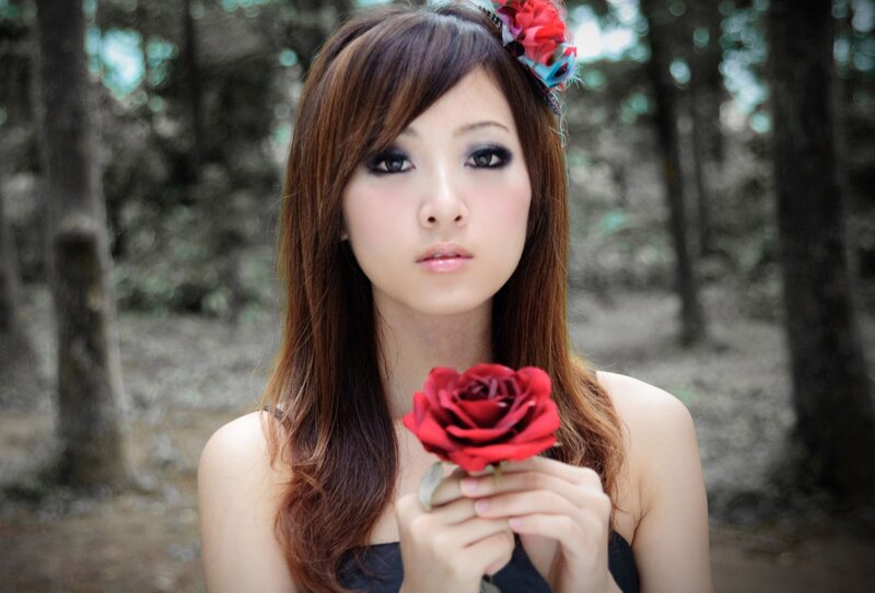 woman holding red rose in forest
