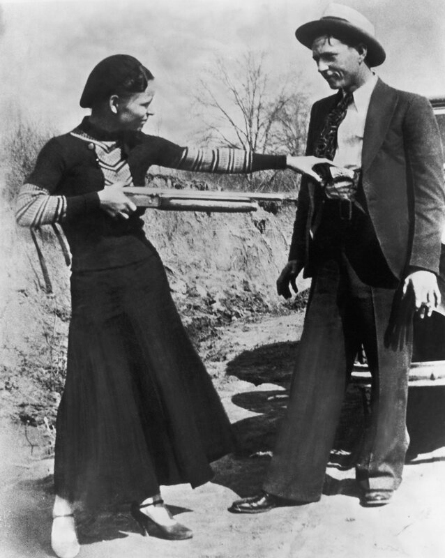 Woman holding rifle to man