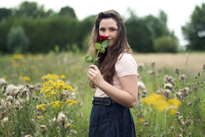 woman holding rose in field