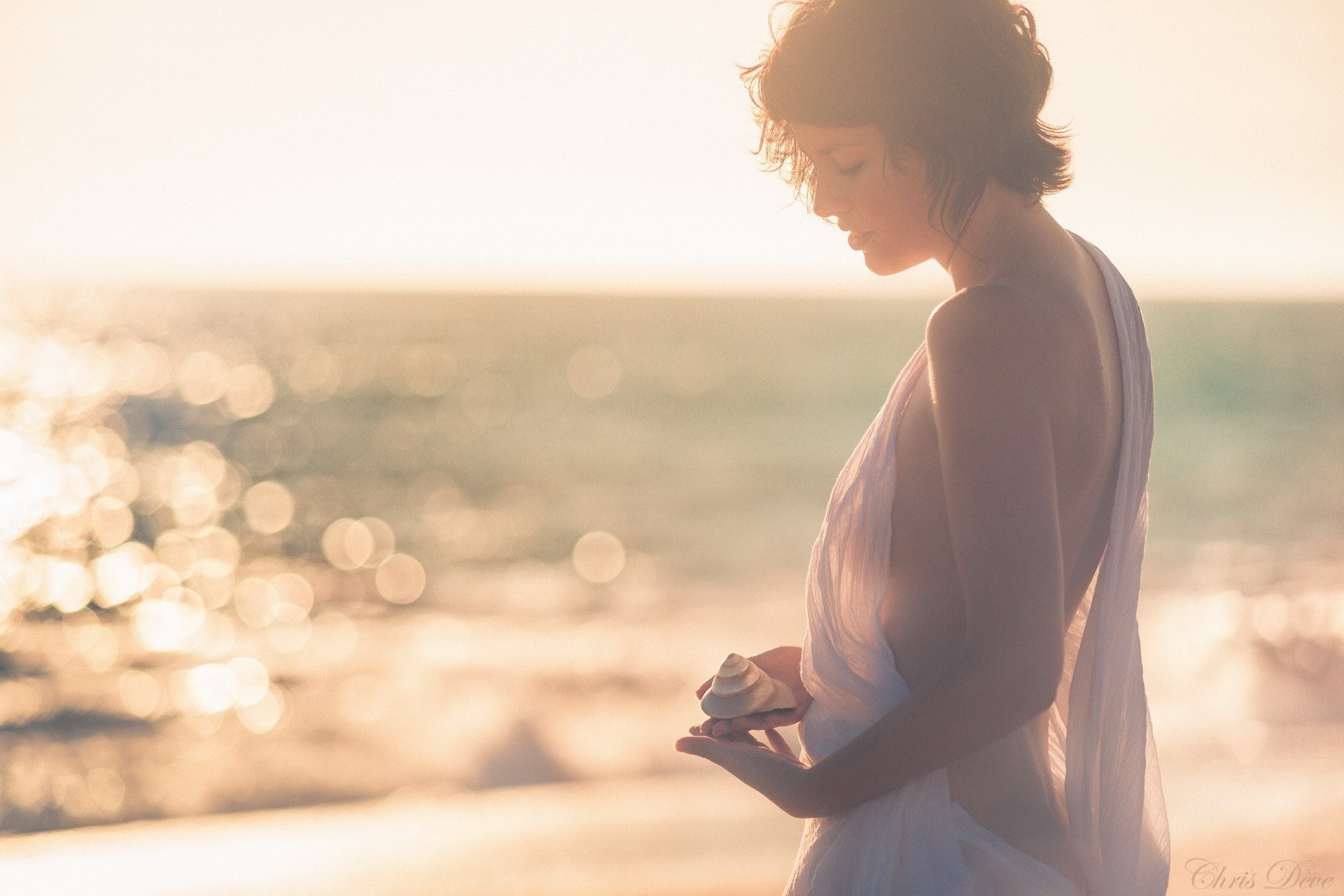 woman holding shell at sunset