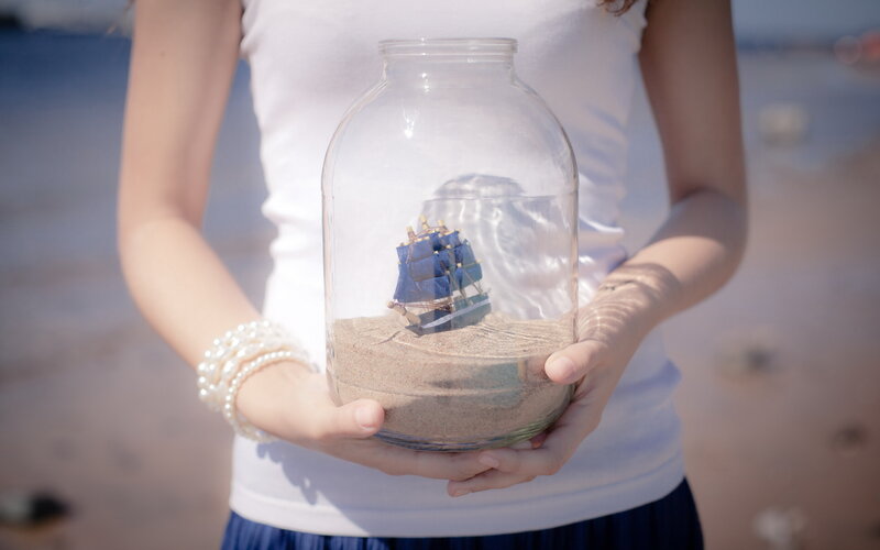 Woman Holding Ship in Jar