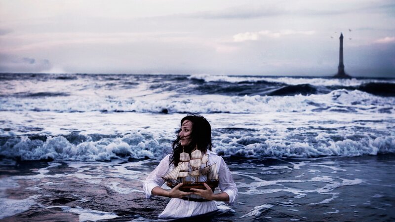 Woman holding ship model in ocean
