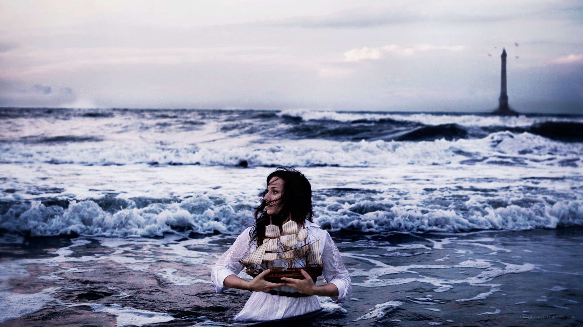 Woman holding ship model in ocean