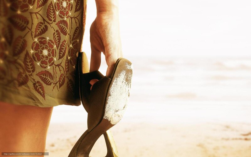 woman holding shoes on beach