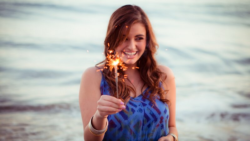 woman holding sparkler at beach