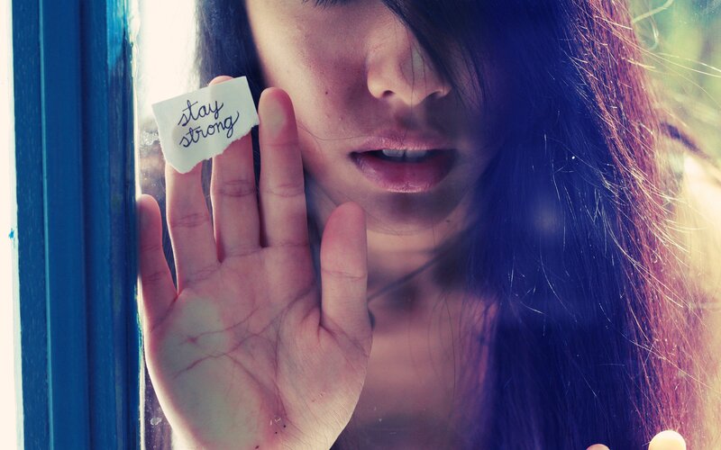 woman holding 'stay strong' note