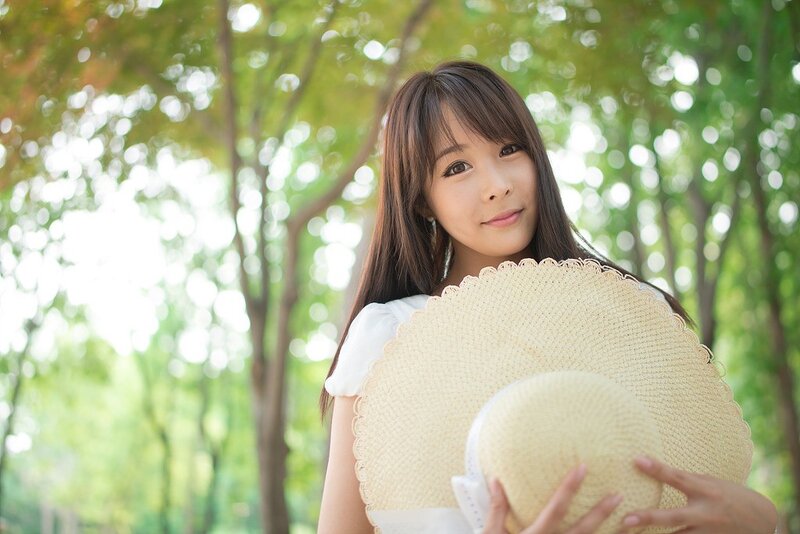 woman holding straw hat in park