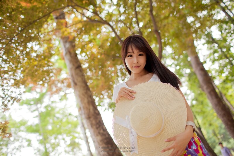 woman holding straw hat in park