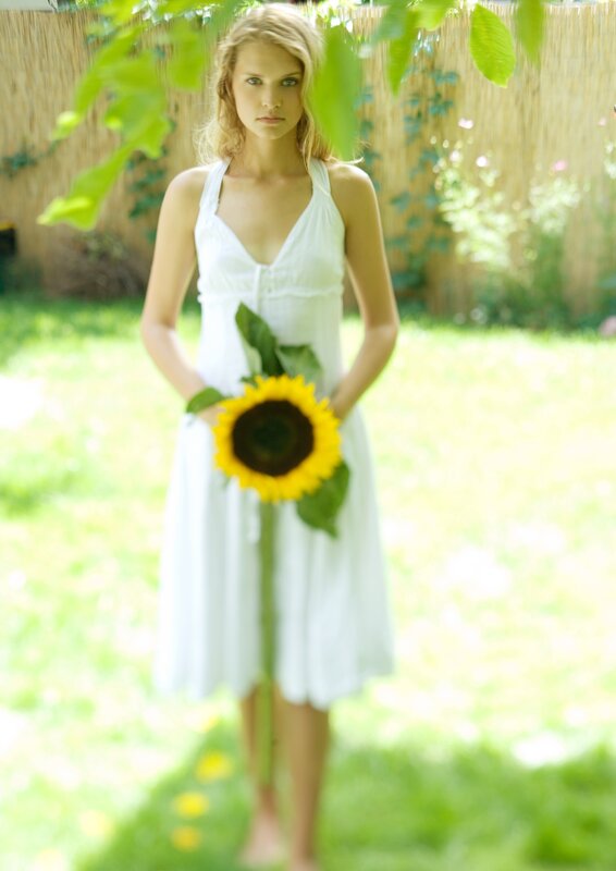Woman holding sunflower in garden