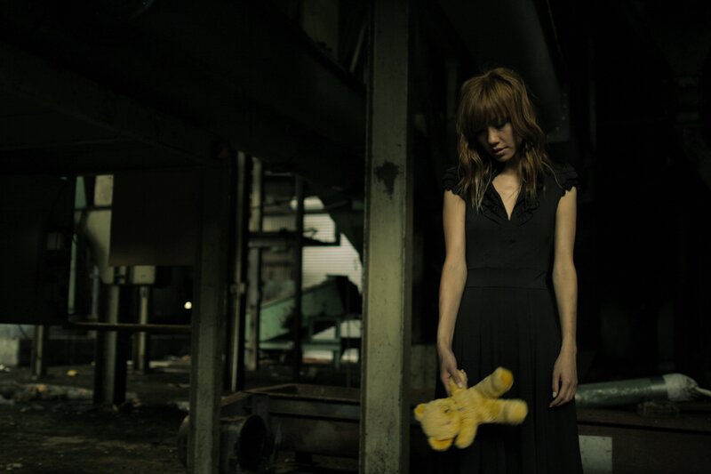 woman holding teddy bear in dark room